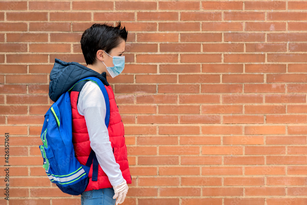 sad and pensive kid with protective surgical mask and backpack going to school sad and pensive kid with protective surgical mask and backpack going to school