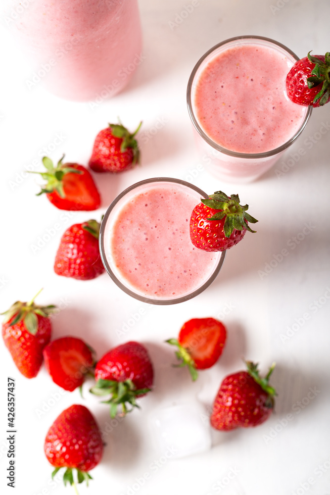Fresh homemade cold strawberry smoothie with ice cubes and fresh strawberries on white background. Top view. Fresh homemade cold strawberry smoothie with ice cubes and fresh strawberries on white background. Top view.