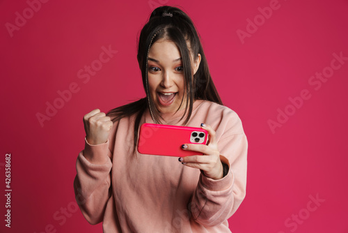 Asian brunette excited woman playing online game on mobile phone