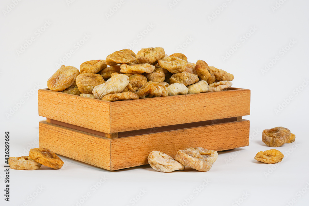  Dried figs on white background. Natural dried figs in wooden box. Studio light. Sun dried fruits. Copy space. Health, organic concept.