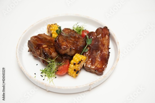 Delicious grilled pork ribs in BBQ sauce with herbs, isolated on white background