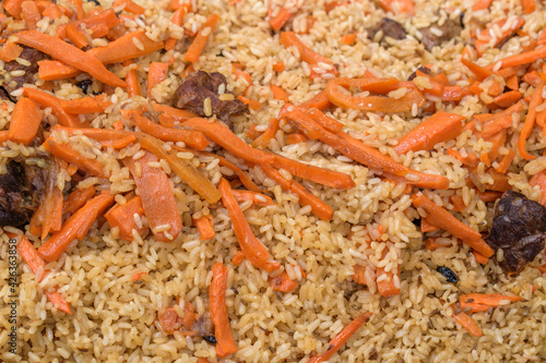 Ready dish - pilaf close-up for the backdrop. Carrots  rice  meat  spices. The concept of an oriental traditional hearty dish.