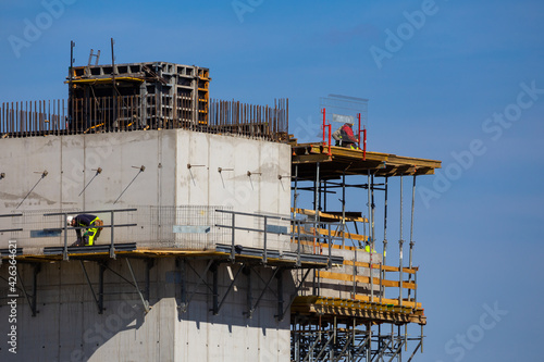 Workers working at height on the construction of a public facility. Collection of structural elements from the construction crane sling. Photo taken on a sunny day. Grodzisk Mazowiecki, Poland photo