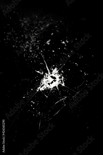 Cracked glass, hole and crack on a black background.Broken glass. Concept for copy and edit.