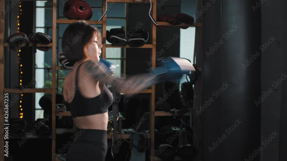 Tattooed woman training her punches on the punching bag Tattooed woman training her punches on the punching bag
