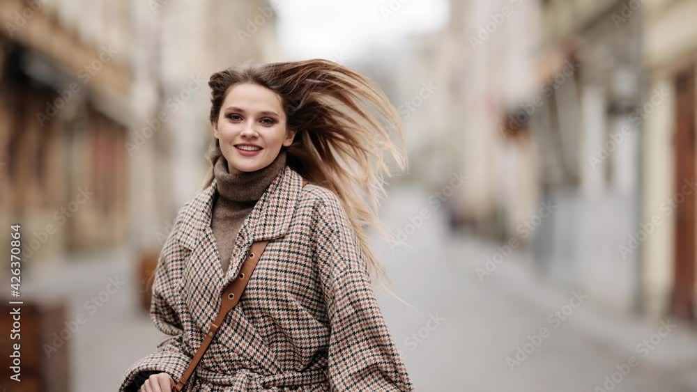 Young beautiful blonde woman runing on city street, she looking to camera and smiles. Outdoor portrait happy female tourist having good time wandering around town Young beautiful blonde woman runing on city street, she looking to camera and smiles. Outdoor portrait happy female tourist having good time wandering around town