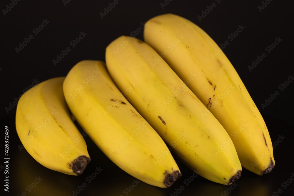 The four ripe bananas on a black background isolated. Close-up vitamin.
