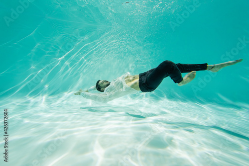 Arabian man in white shirt swimming underwater in pool © LIGHTFIELD STUDIOS