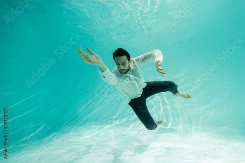 Wallpaper Mural Young muslim businessman with closed eyes swimming under water in pool Torontodigital.ca
