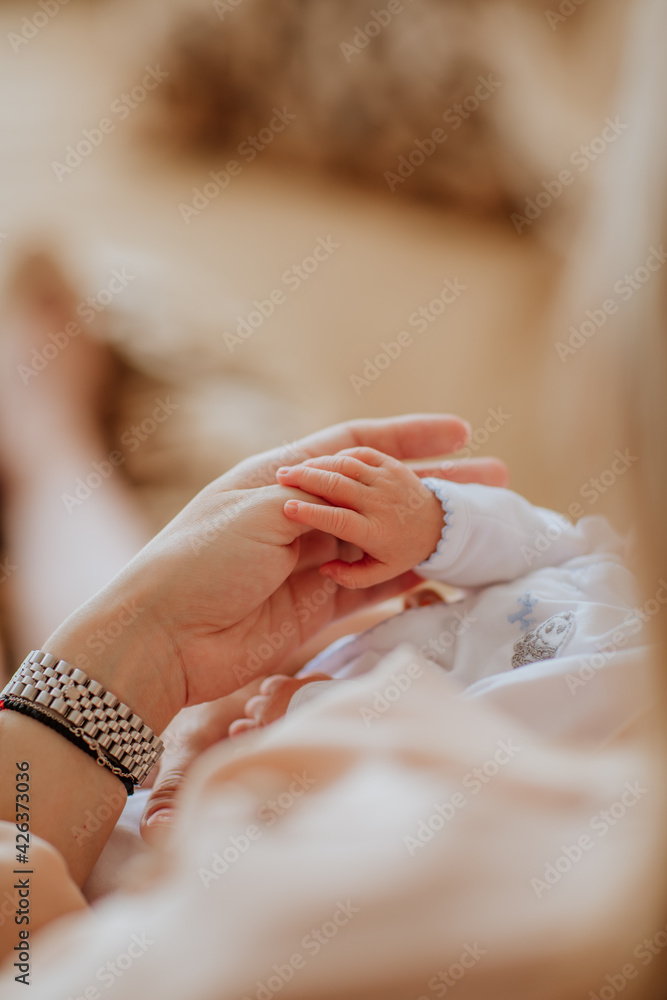 Obraz premium Mother's hand holding little newborn baby's hand.
