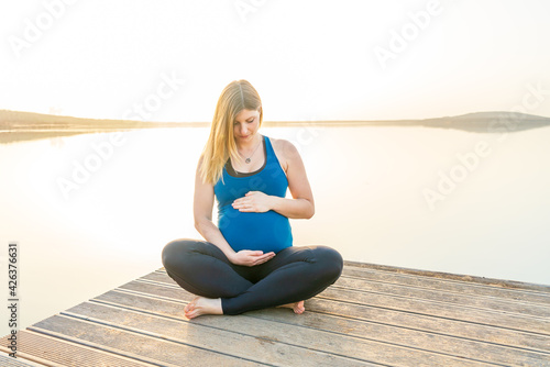 Portrait of a young happy pregnant woman on a jetty during a beautiful sunset © DZiegler