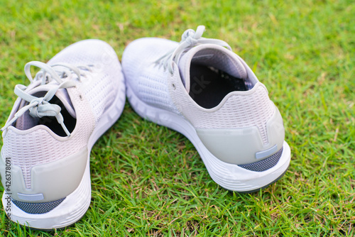 White running shoe on green football grass field © themorningglory