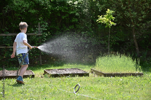 Junge gießt den Garten mit dem Gartenschlauch