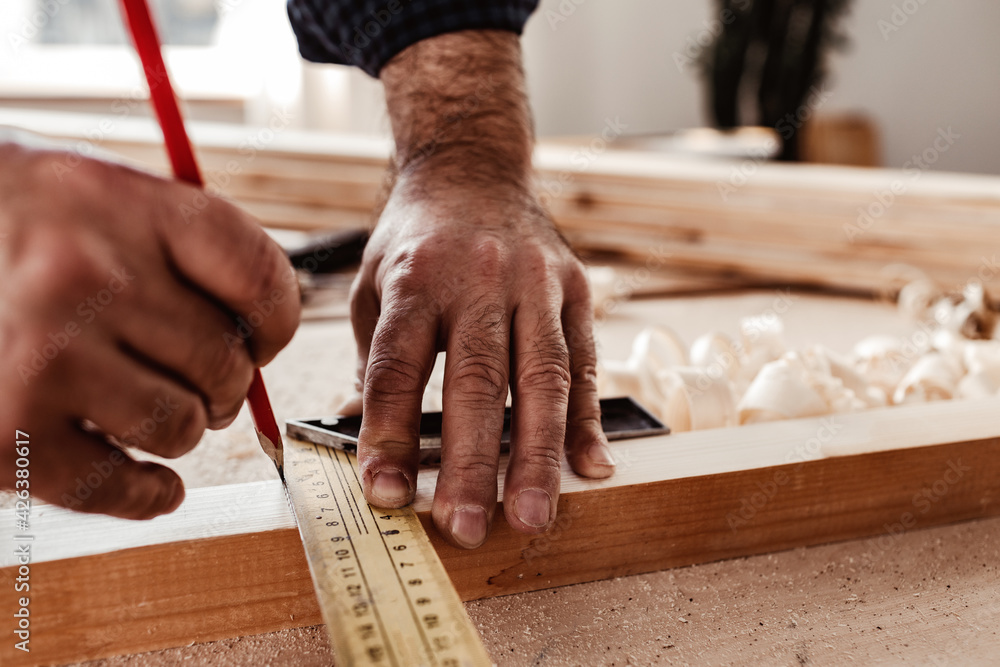Carpenter makes pencil marks on a wood plank Carpenter makes pencil marks on a wood plank
