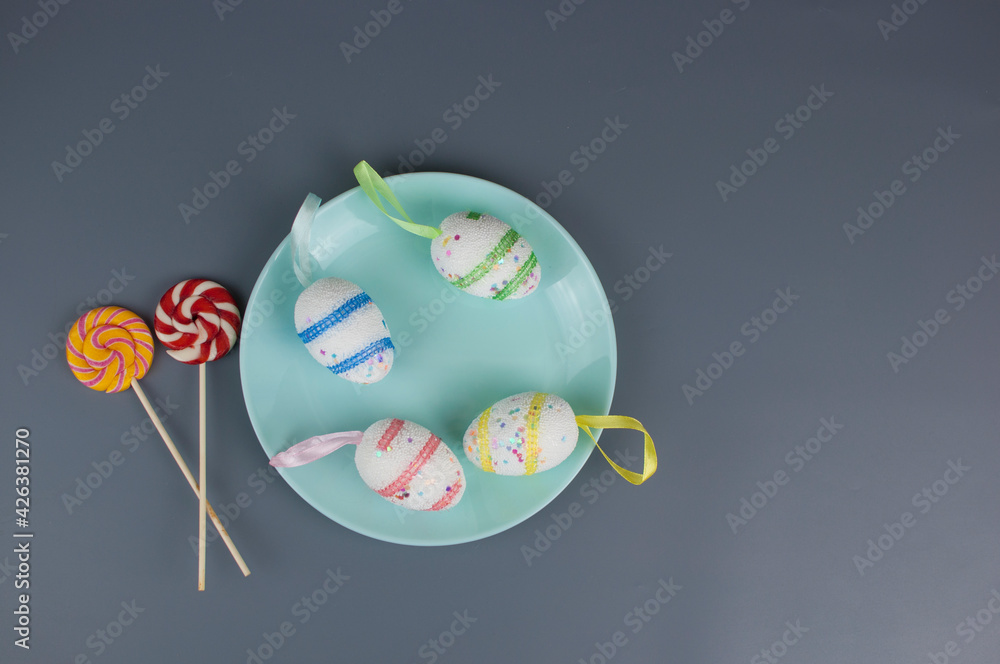 Colorful Easter eggs on ceramic round plate with colorful napkin. View from above, top with copy space.