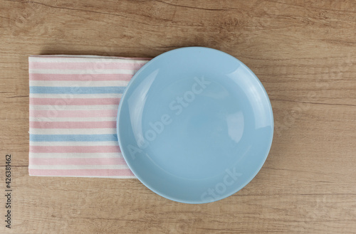 Empty plate and towel over wooden table background. View from above with copy space