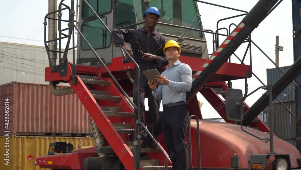 business man using laptop checking list inventory loading Containers box discussion with african american foreman diver on forklift at warehouse logistic in Cargo freight ship. diversity worker business man using laptop checking list inventory loading Containers box discussion with african american foreman diver on forklift at warehouse logistic in Cargo freight ship. diversity worker