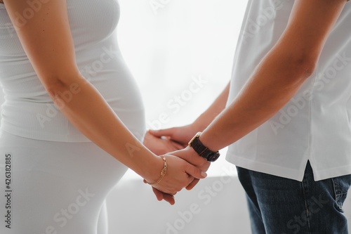 Image of pregnant couple. Husband touching his wife belly with hands