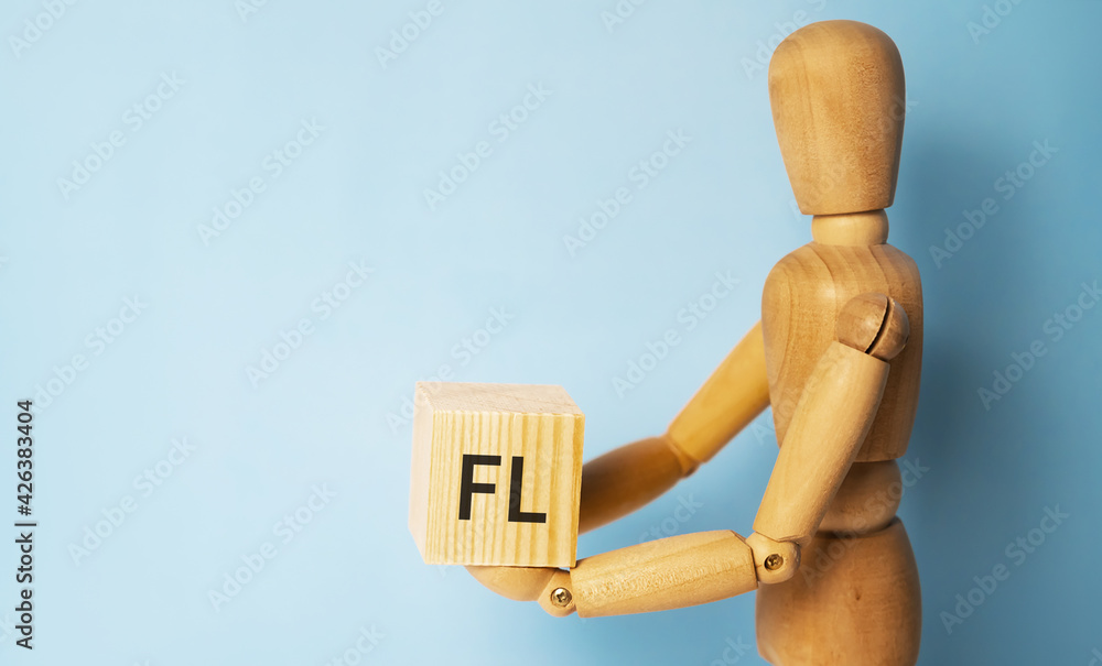 Wooden man holding a wooden cube with acronym FL-Financial leverage. Business and finances concept. Wooden man holding a wooden cube with acronym FL-Financial leverage. Business and finances concept.