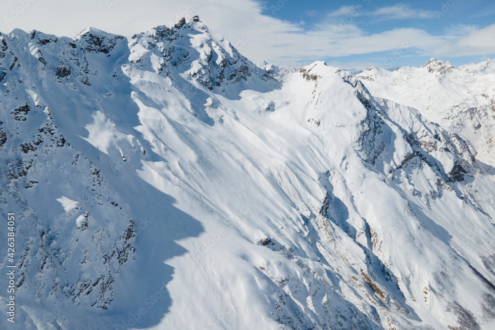 Aerial view of Elbrus and Cheget canyon mountains in snow in winter upon the clouds, climbing and mountain skiing
