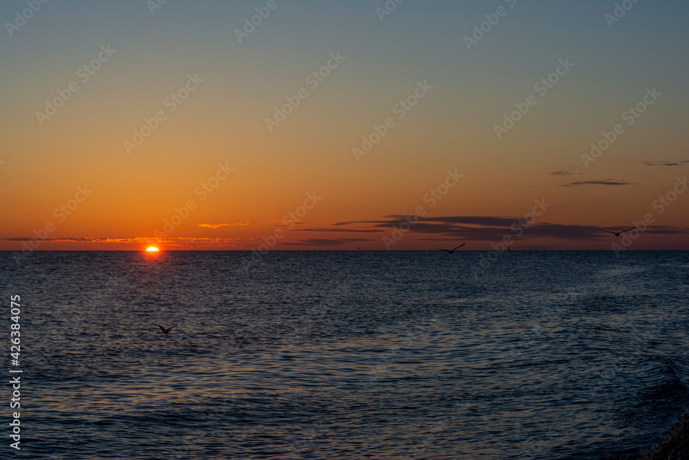 colorful sunset with a cloudless sky overlooking the sea and the setting bright sun