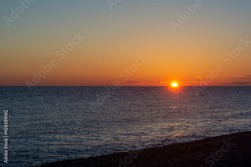 colorful sunset with a cloudless sky overlooking the sea and the setting bright sun