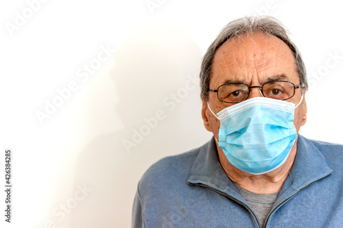 Old man with foggy eye glasses due to condensation caused by the use of a protective face mask. Senior man with foggy glasses. The effects of wearing a mask for people that must wear glasses.