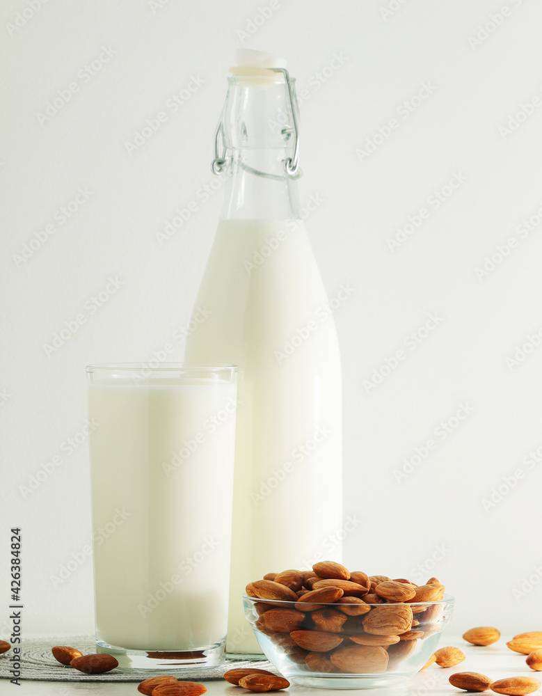 A glass with almond milk and the bowl with almonds A glass with almond milk and the bowl with almonds