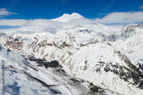 Aerial view of Elbrus and Cheget mountains in snow in winter upon the clouds, climbing and mountain skiing
