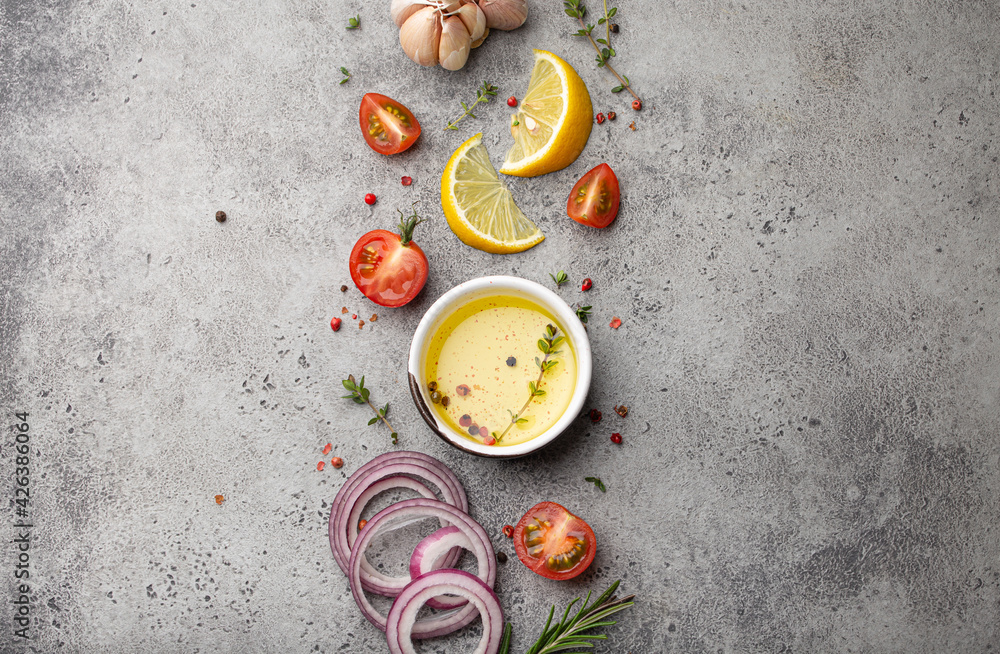 Food cooking ingredients arranged on grey stone rustic table with healthy vegetables, herbs, spices, olive oil from above