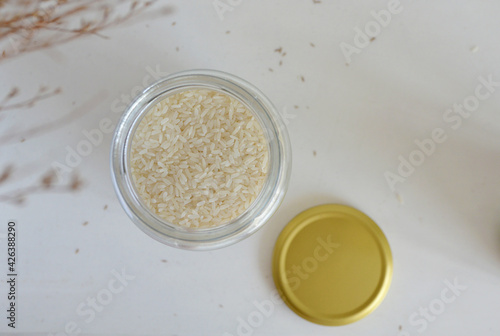 Jar of white Vietnamese jasmine infused rice with brass gold lid. View from top against white background. 