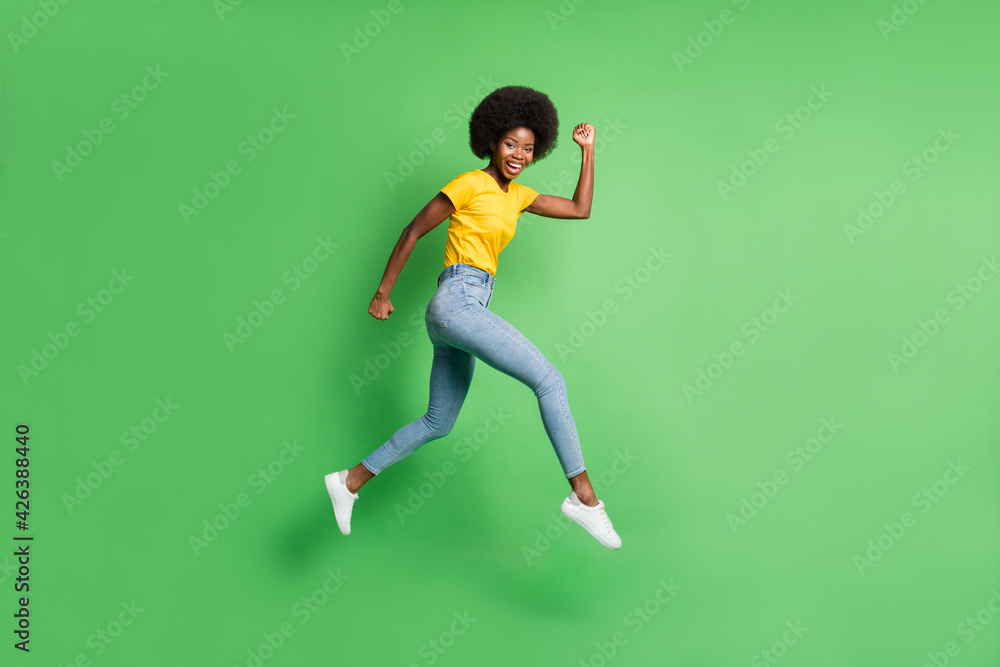 Full length body size side profile photo of jumping girl running fast smiling isolated on vivid green color background Full length body size side profile photo of jumping girl running fast smiling isolated on vivid green color background