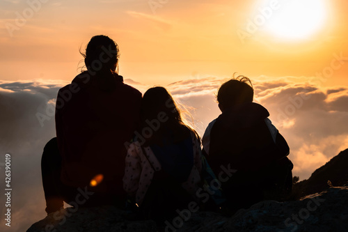 Madre e hijos disfrutando juntos del atardecer en lo alto de la montaña.