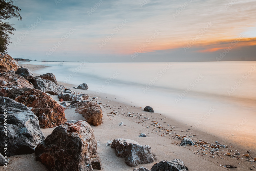 long exposure Sea rocks Magnificent sunrise view at sunrise Romantic atmosphere in peaceful morning at sea. Pink horizon with first hot sun rays.
