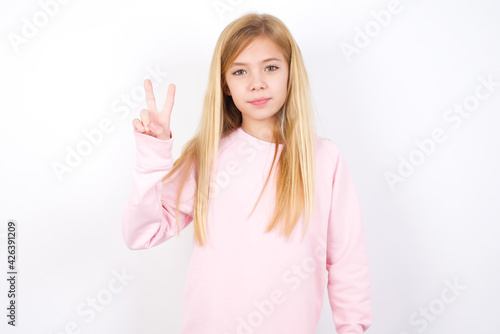 beautiful caucasian little girl wearing pink hoodie over white background showing and pointing up with fingers number two while smiling confident and happy.