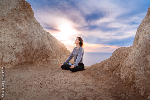 Woman meditating and doing yoga at sunrise