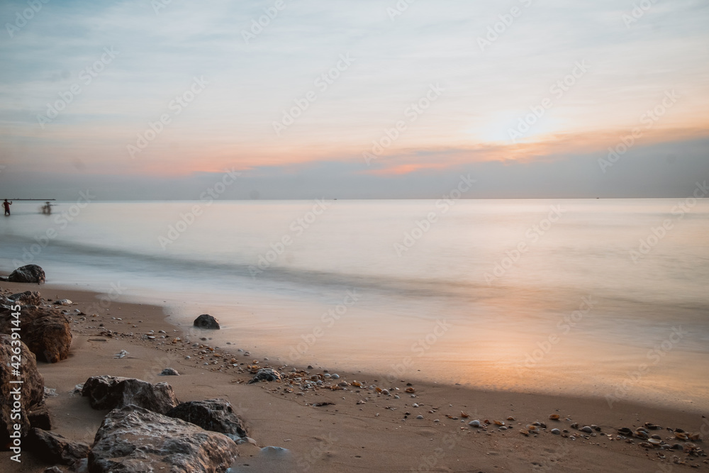 Fototapeta premium long exposure Sea rocks Magnificent sunrise view at sunrise Romantic atmosphere in peaceful morning at sea. Pink horizon with first hot sun rays.