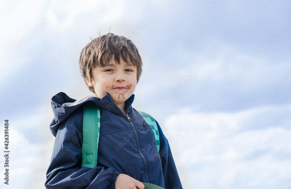 Kid with dirty mouth of chocolate ice cream with blurry sky background,Candid shot happy child standing alone with smiling face. A boy playing outdoor in sunny day summer,World Children s Day Kid with dirty mouth of chocolate ice cream with blurry sky background,Candid shot happy child standing alone with smiling face. A boy playing outdoor in sunny day summer,World Children s Day