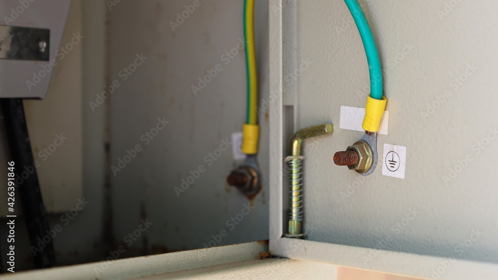 Close up the ground wire in a metal box. The gray breaker box has a