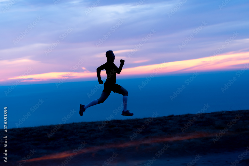 Running man silhouette on sunset sky backdrop