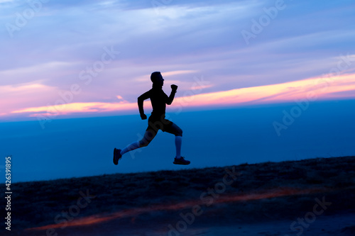 Running man silhouette on sunset sky backdrop