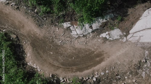 Mountain biker take quick turn in aerial bird eye view on rocky trail downhill freeride trail terrain in the forest photo