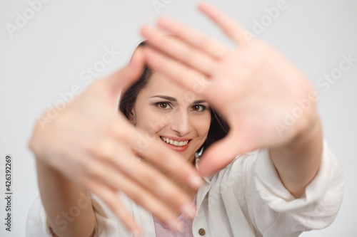 Hand framing woman portrait. Selective focus on face