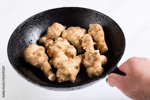 Hand hold pan with jerusalem artichokes. Jerusalem artichokes on frying pan.
