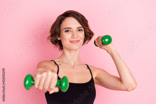 Photo of cheerful young nice pretty woman punch hold dumbbells smile gym isolated on pink color background