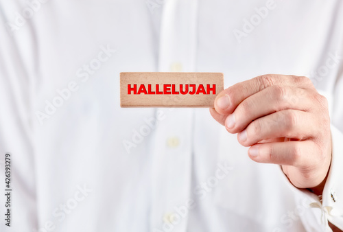 Leinwand Poster Male hand holds a wooden block with the word hallelujah.