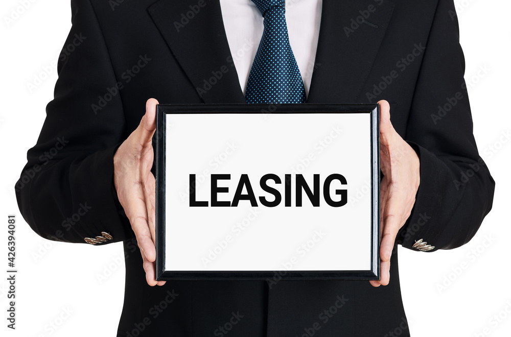 Businessman holds a signboard with the word leasing on isolated white background. Business finance Businessman holds a signboard with the word leasing on isolated white background. Business finance