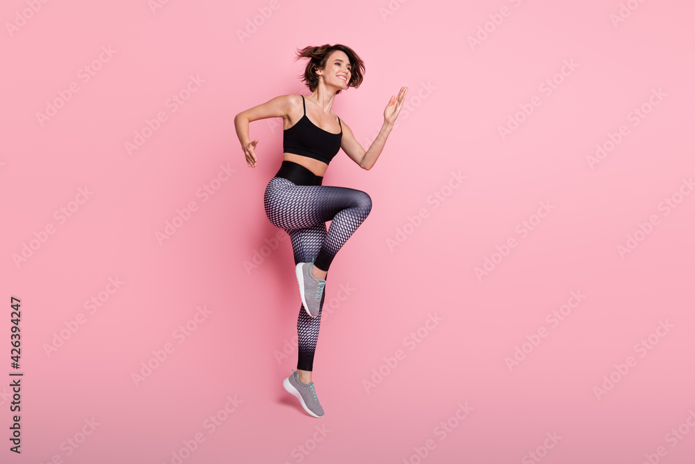 Full length profile side photo of young sportive girl go walk run cross fit dynamic isolated over pink color background Full length profile side photo of young sportive girl go walk run cross fit dynamic isolated over pink color background