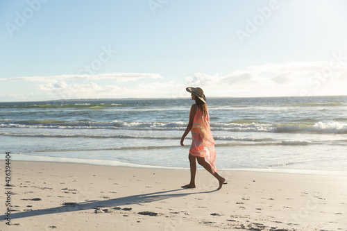 Happy mixed race woman on beach holiday walking