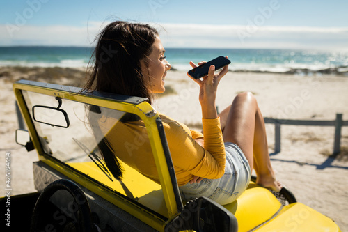 Caucasian woman lying on a beach buggy by the sea talking on smartphone © wavebreak3